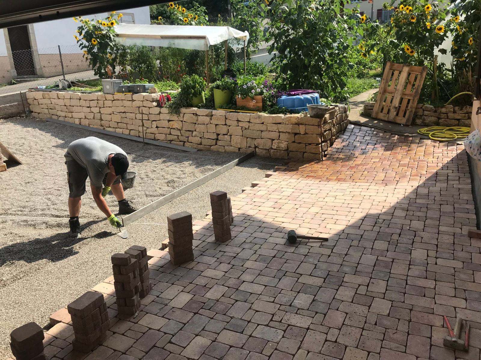 Pose de pavés devant un mur en pierre sèche